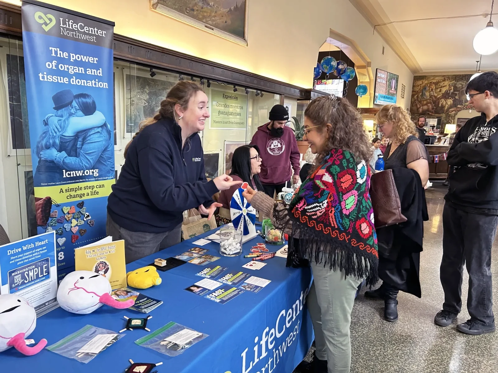 An outreach coordinator sharing organ donation materials with a community member at a tabling event